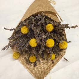 Bundle of dried purple flowers with yellow pom-pom blooms wrapped in burlap