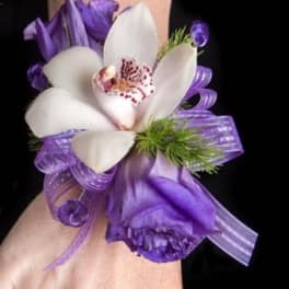 Purple and white orchid corsage with ribbon on a wrist