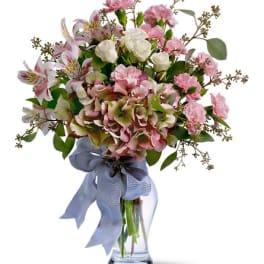 Pink and white mixed bouquet in a clear glass vase with a blue ribbon