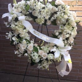 White floral heart wreath on a stand with a ribbon