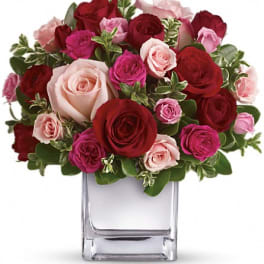 Bouquet of red, pink, and blush roses in a clear glass vase