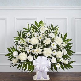 White floral standing spray with a large bow on a pedestal base