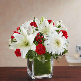 White lilies and daisies with red carnations in a glass vase