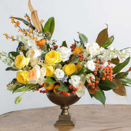 Yellow and white roses arranged in a bronze pedestal vase