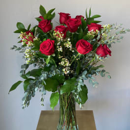 Tall bouquet of red roses in a clear glass vase