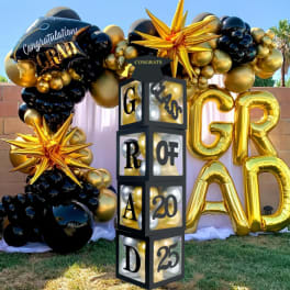 Gold and black graduation balloon display with large GRAD letters