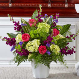 Pink roses and purple flowers arranged in a white vase