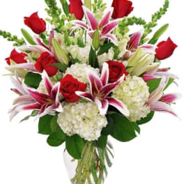 Bouquet of red roses, pink lilies, and white hydrangeas in a glass vase