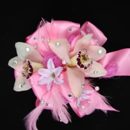 Pink ribbon corsage with pale orchid blooms and decorative feathers