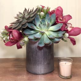 Succulent arrangement with pink orchids in a ribbed metal vase