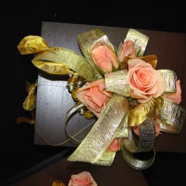 Peach roses with gold ribbon on a dark board