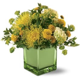 Yellow and white floral arrangement in a green glass vase