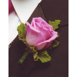 Pink rose boutonniere with green leaves on a dark suit lapel