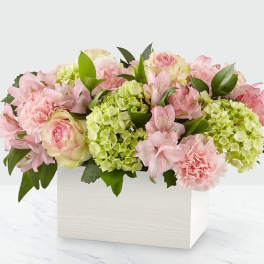 Pink and green floral arrangement in a white box