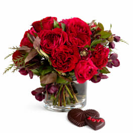 Red rose bouquet in a glass vase with heart-shaped chocolates