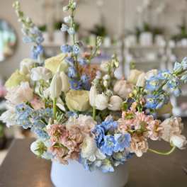 Pastel flower arrangement in a white vase with blue and pink blooms