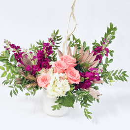 Pink roses and white hydrangea in a white vase with purple flowers