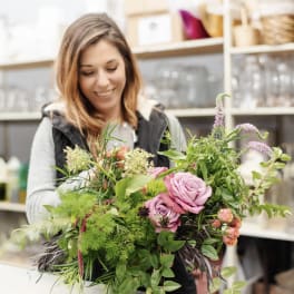 Woman holding a large bouquet of pink roses and greenery