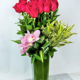 Red roses and pink orchids in a tall glass vase