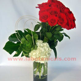 Red roses and white hydrangea in a tall glass vase