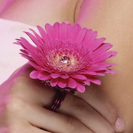 Pink gerbera daisy corsage on a wrist with a jeweled center