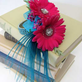 Two pink gerbera daisies on stacked books with blue ribbon accents