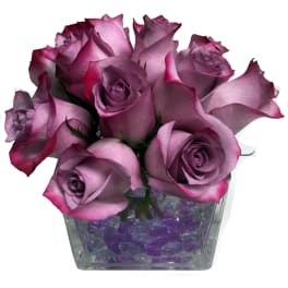 Bouquet of lavender roses in a square glass vase with purple stones