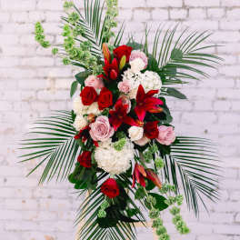 Standing floral spray with red and pink roses and lilies on an easel
