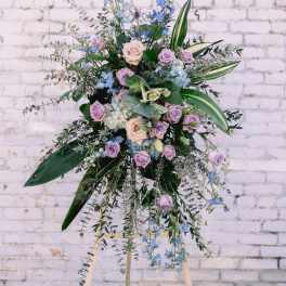 Tall floral spray with lavender and blue flowers on an easel