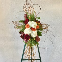 Tall floral arrangement with white and orange blooms on a green stand