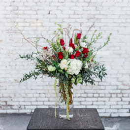 Tall bouquet of red and white flowers in a clear glass vase