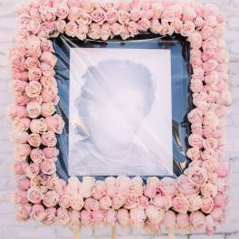 Square floral frame of pale pink roses around a portrait on an easel