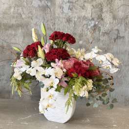 Red roses and white orchids arranged in a white vase