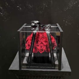 Red roses in a clear square box tied with a black ribbon