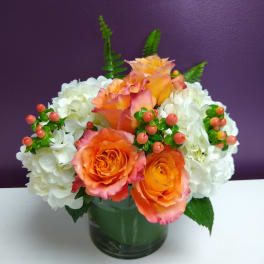 Orange roses and white hydrangeas in a glass vase
