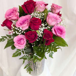 Tall arrangement of red and pink roses with baby's breath in a silver textured vase