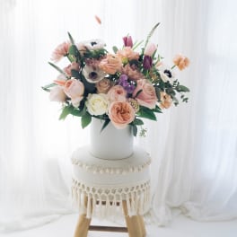 Pastel flower arrangement in a white vase on a stool