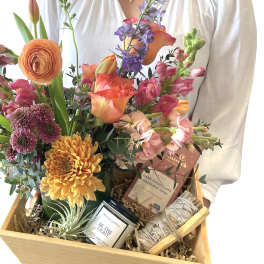 Mixed flower gift basket with candles and chocolate in a wooden crate