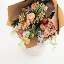 Wrapped bouquet of peach and pink flowers with mixed blooms