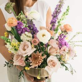 Mixed bouquet in a brass bowl with peach, white, and purple flowers