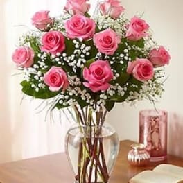 Pink roses arranged in a clear glass vase with baby's breath