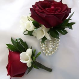 Two red rose boutonnieres with white accents and pearl strands