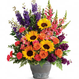 Mixed bouquet with sunflowers, roses, and purple spikes in a gray vase