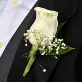 White rose boutonniere with baby's breath on a black suit lapel