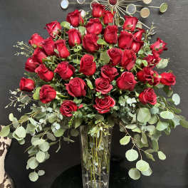 Tall vase arrangement of red roses with eucalyptus