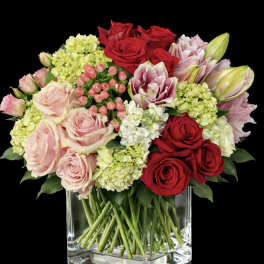 Bouquet of red and blush roses with pale hydrangeas in a clear glass vase