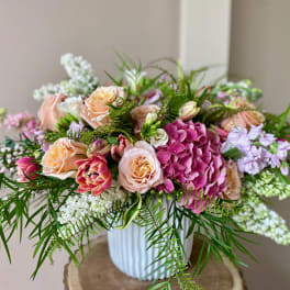 Pink and peach roses with hydrangeas in a white vase