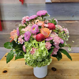 Pink and peach bouquet in a white vase with green hydrangea and red ornaments