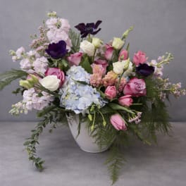 Mixed pink, white, and purple flowers arranged in a white bowl vase