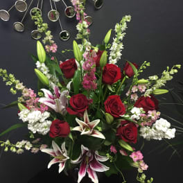 Bouquet of red roses, white lilies, and pink filler flowers in a vase